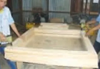 Dua pekerja merakit rangka peti kayu